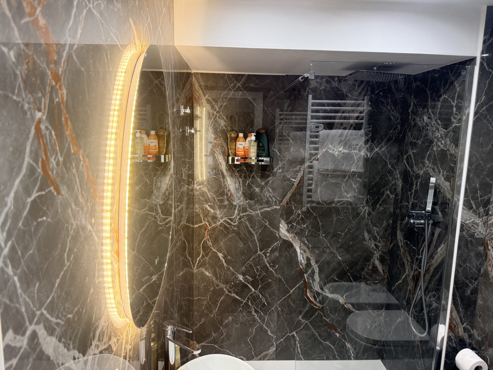 Il bagno in marmo scuro con specchio retroilluminato